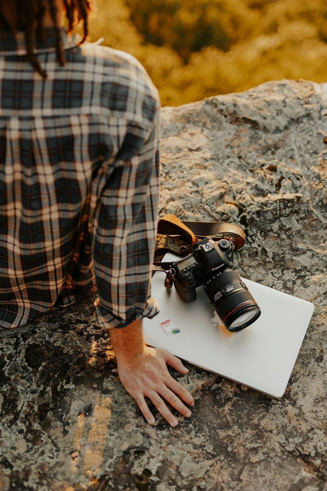 Photographer editing photographs on a laptop next to a camera
